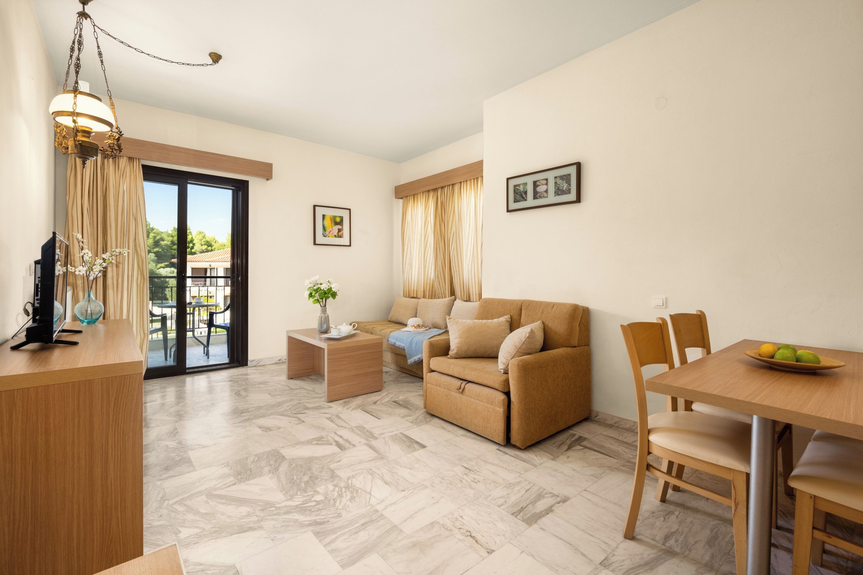 A modern living room with a sofa, a dining table with chairs, a TV, and a balcony with a table and chairs.
