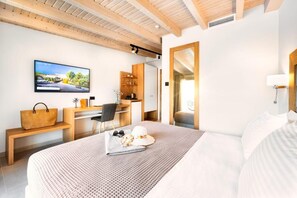 A modern hotel room with a large bed, a desk with a computer, a TV mounted on the wall, and a wooden ceiling. - Chrousso Village (Kassandra)