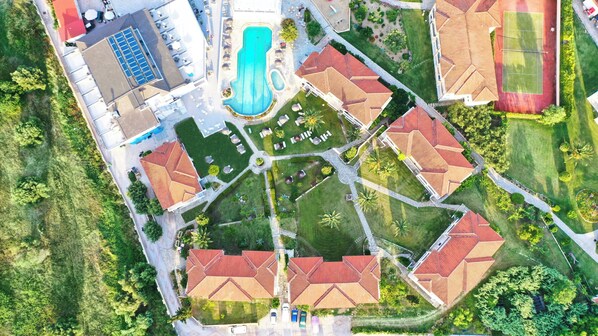 An aerial view of a residential area with multiple houses, a swimming pool, and a tennis court.