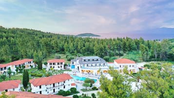 A resort with multiple buildings, a swimming pool, and a forested backdrop.