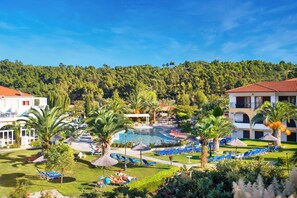 A resort with a swimming pool, sun loungers, and a mountainous backdrop. - Chrousso Village (Kassandra)