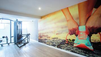 Un gimnasio con equipo de ejercicio y un gran mural de una persona atándose zapatillas para correr.