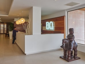 A reception desk with a 'BQ' sign, a statue of a man on a horse, and a modern interior design. - BQ Can Picafort Hotel (Santa Margalida)