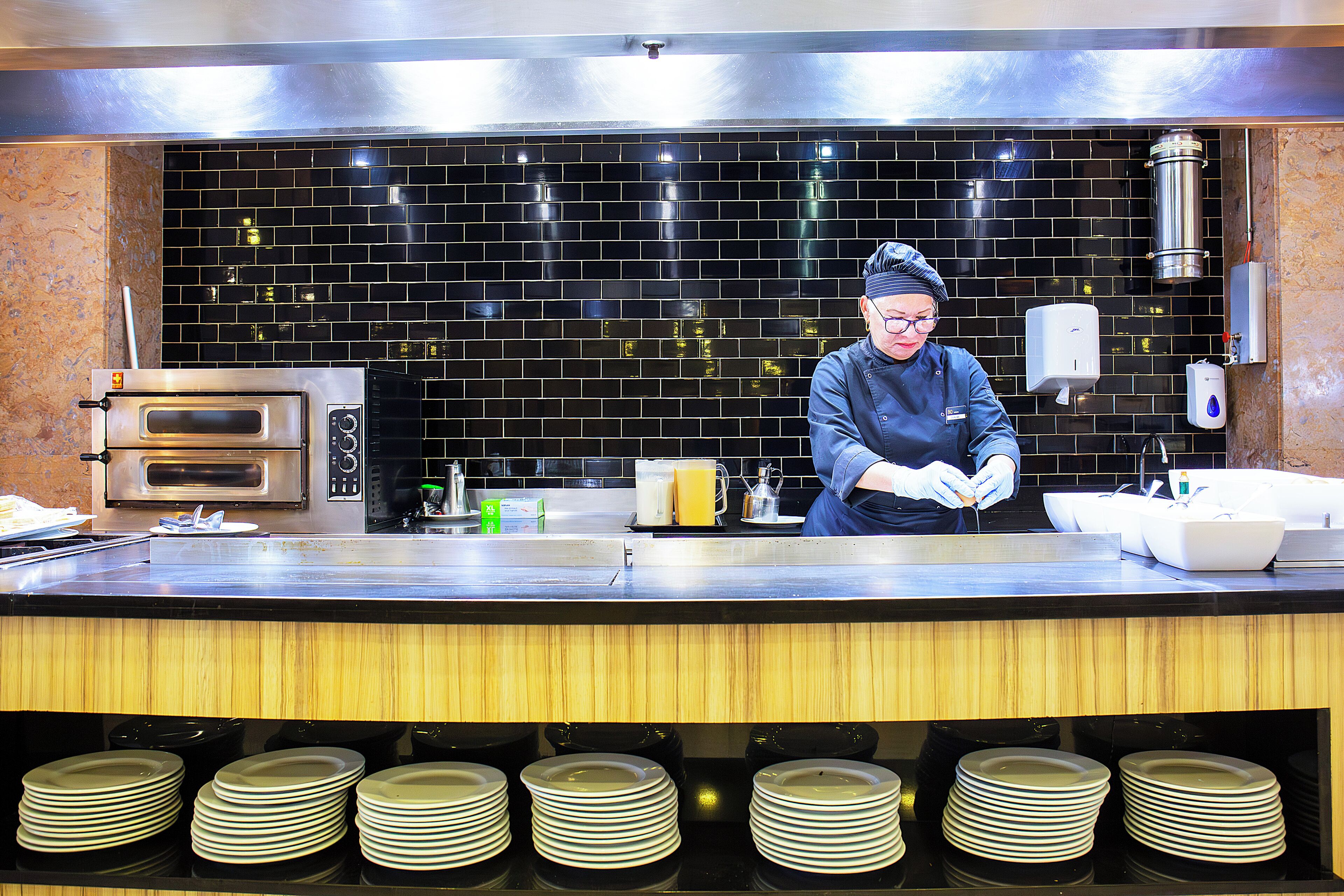 A commercial kitchen with a chef preparing food, a coffee machine, and a sink.