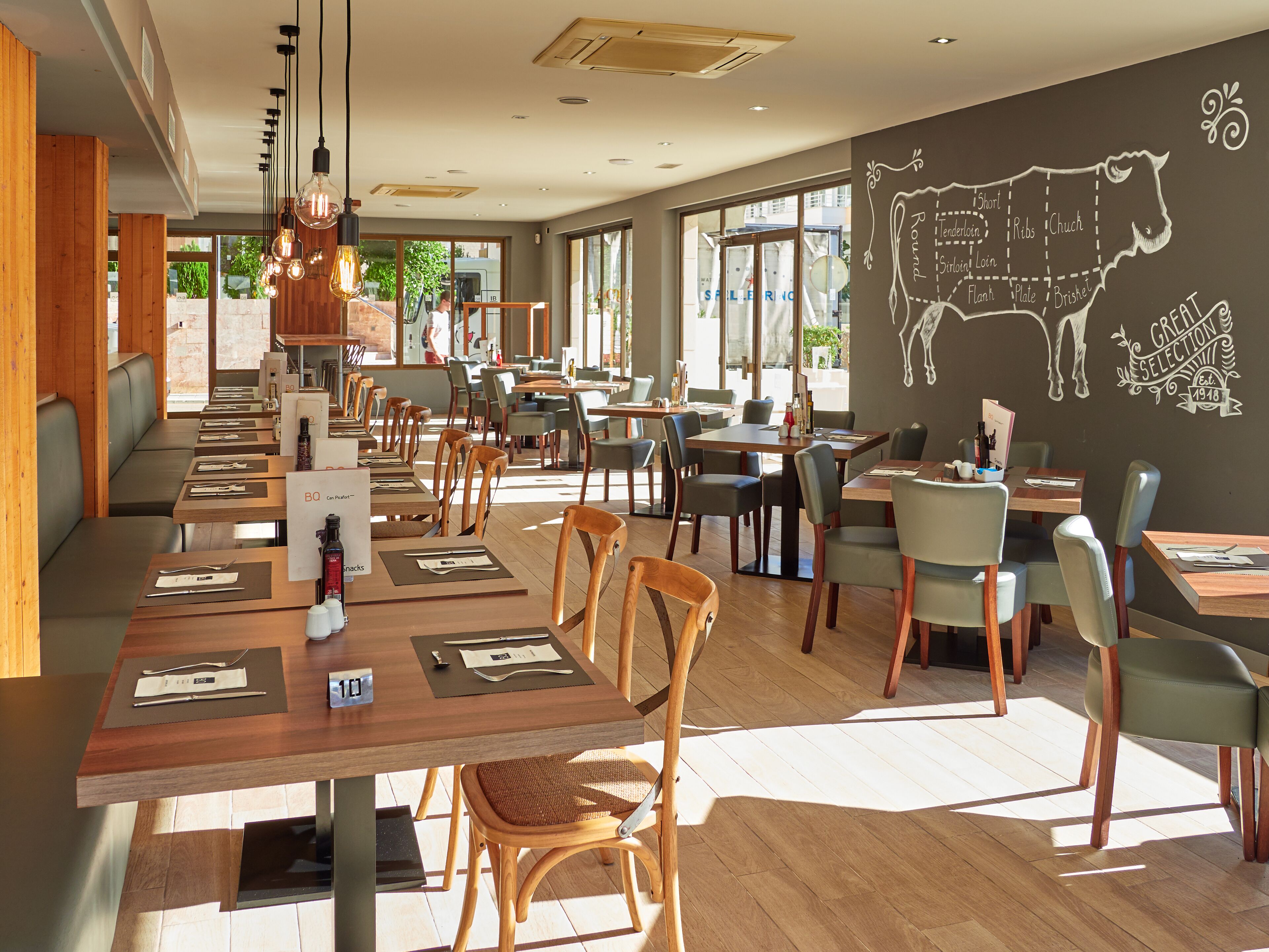 A restaurant with wooden tables and chairs, a chalkboard menu, and a large window.