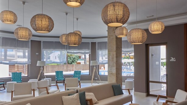 A modern hotel lobby with a large sofa, wooden stools, and hanging wicker lamps. - BQ Can Picafort Hotel (Santa Margalida)