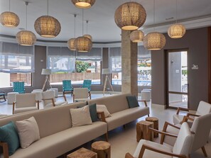 A modern hotel lobby with a large sofa, wooden stools, and hanging wicker lamps. - BQ Can Picafort Hotel (Santa Margalida)