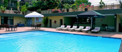 A swimming pool with lounge chairs and a covered seating area.
