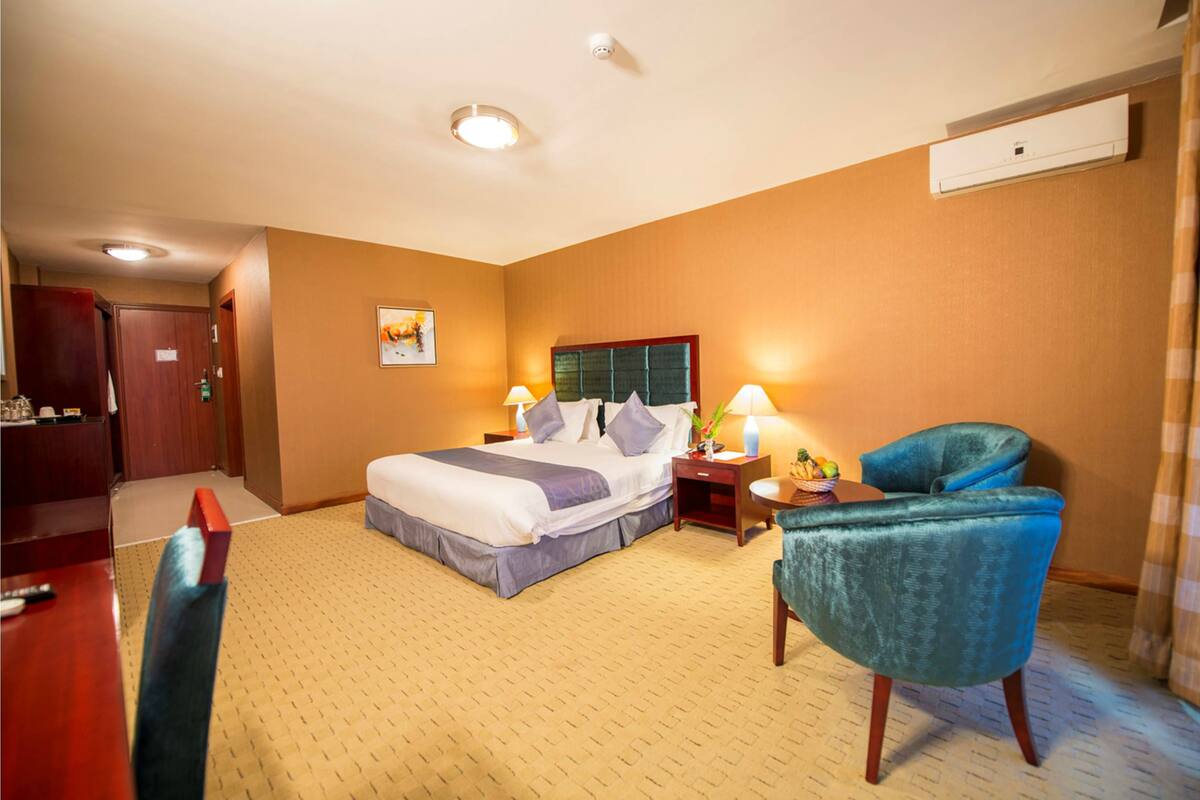 A hotel room with a bed, bedside tables, a chair, and a desk.