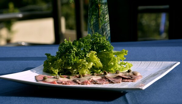 A plate of food with greens and meat on a tablecloth. - Hotel Villa Portofino Kigali (Kigali)