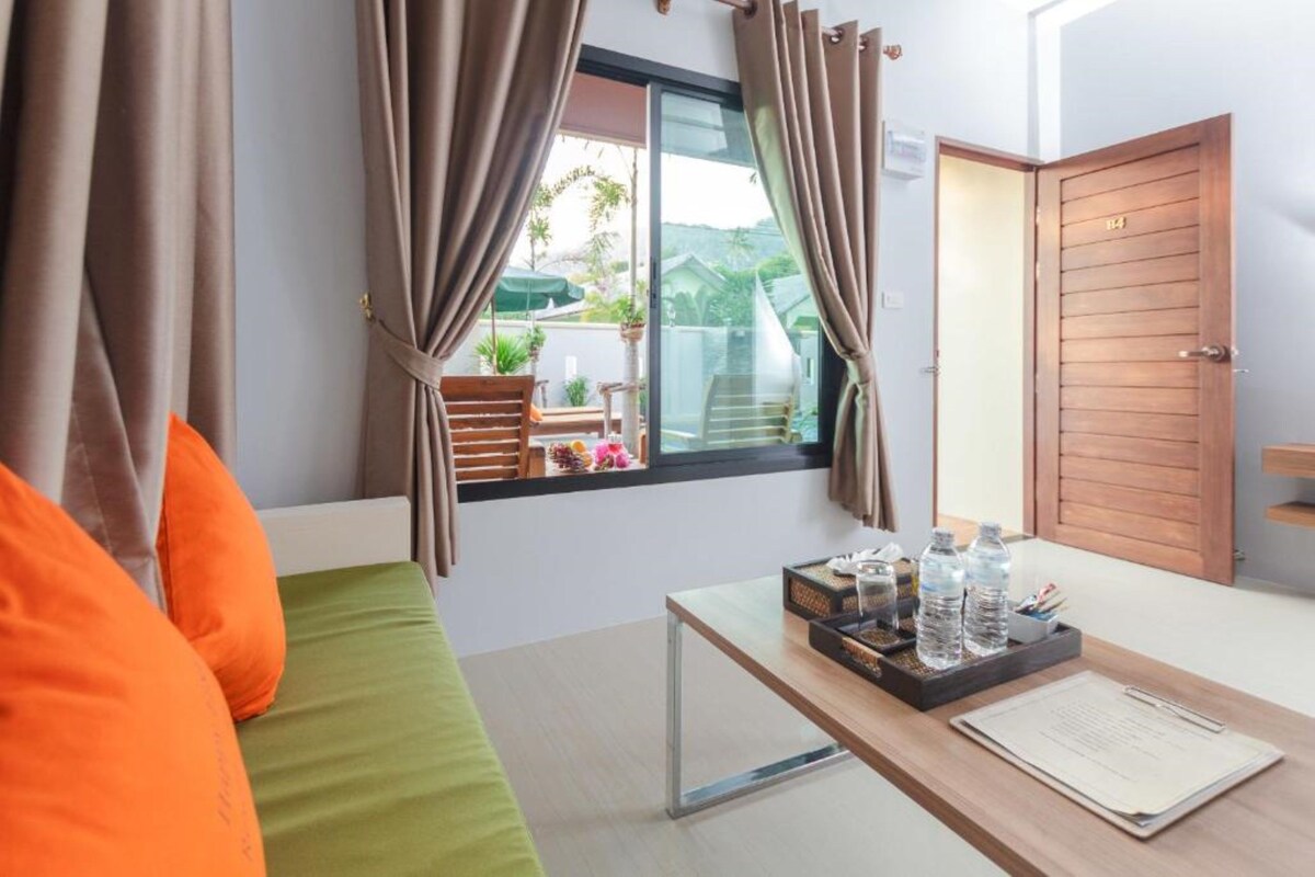 Una habitación de hotel con cama, escritorio y bandeja de botellas de agua, además de una ventana con cortinas.