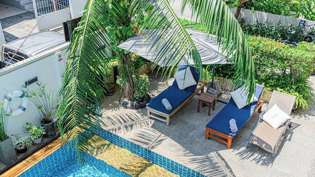 A rooftop pool area with lounge chairs, a small table, and potted plants. - Happy Eight Resort (Rawai)