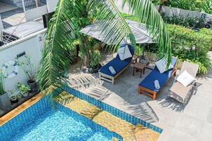 Una piscina al aire libre, sombrillas, sillones reclinables de piscina