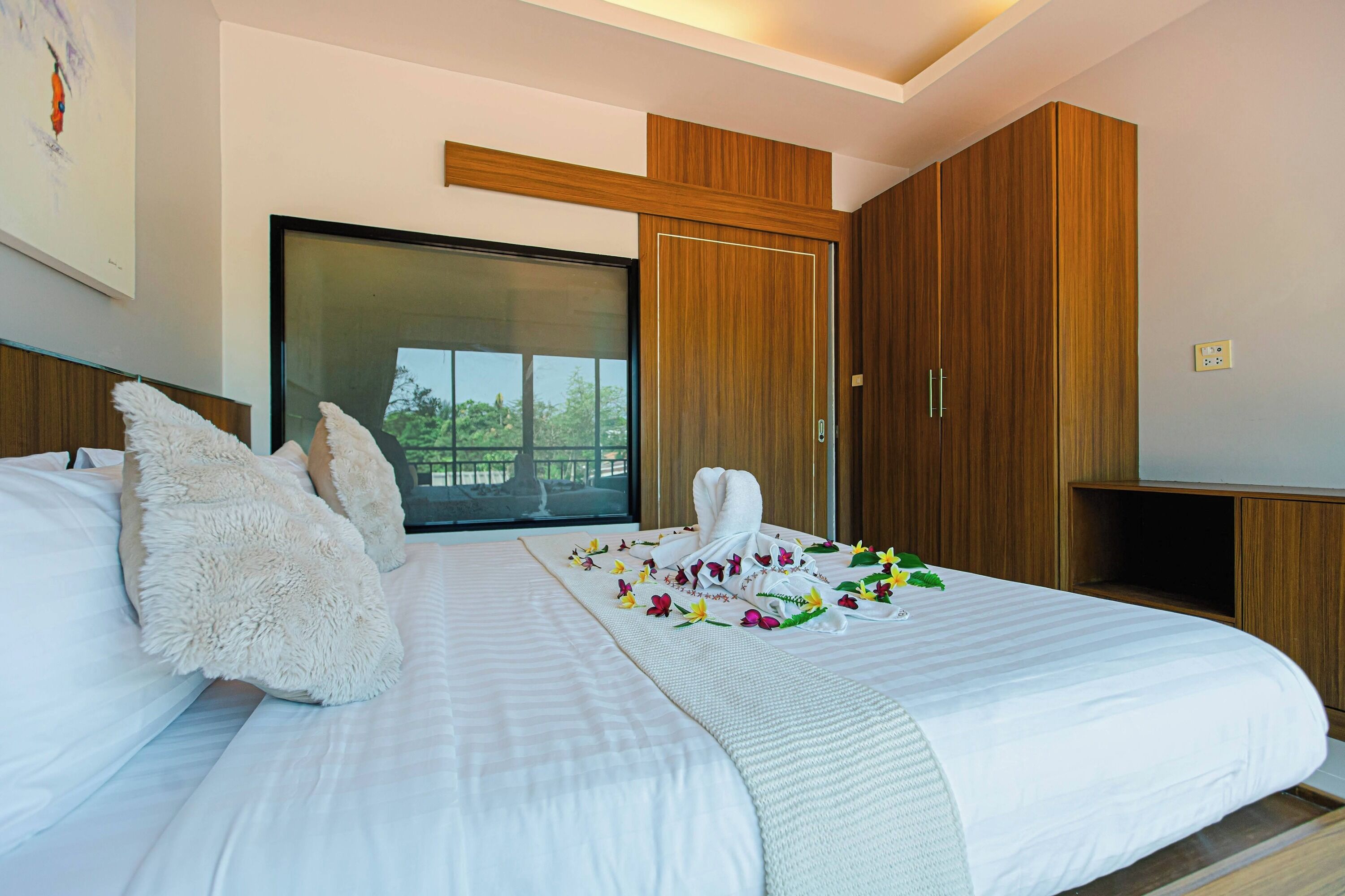 A hotel room with a large bed, a wooden wardrobe, a television, and a window with a view.