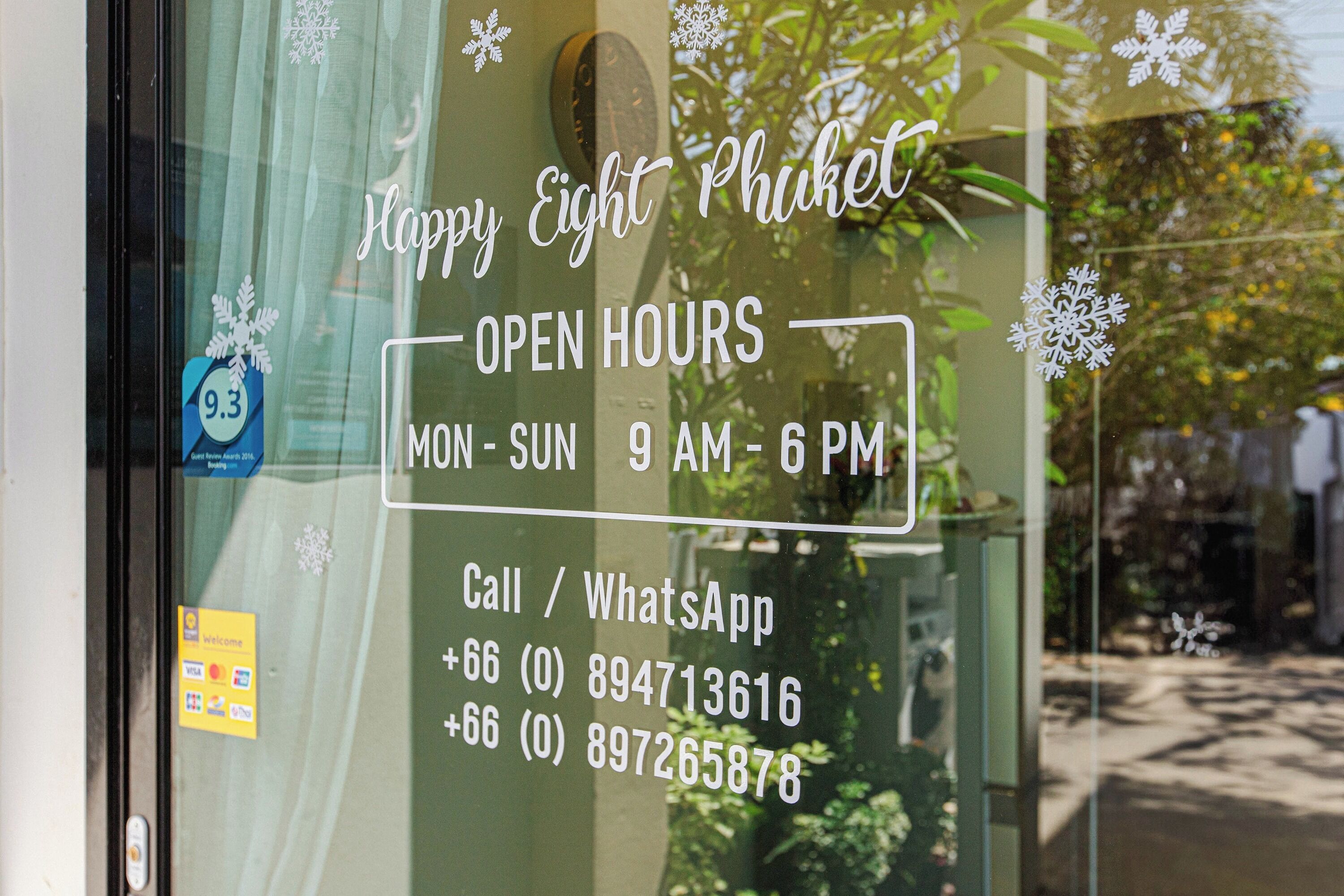 A window with a sign indicating 'Happy Eight Phuket' and 'OPEN HOURS MON-SUN 9 AM-6 PM'.