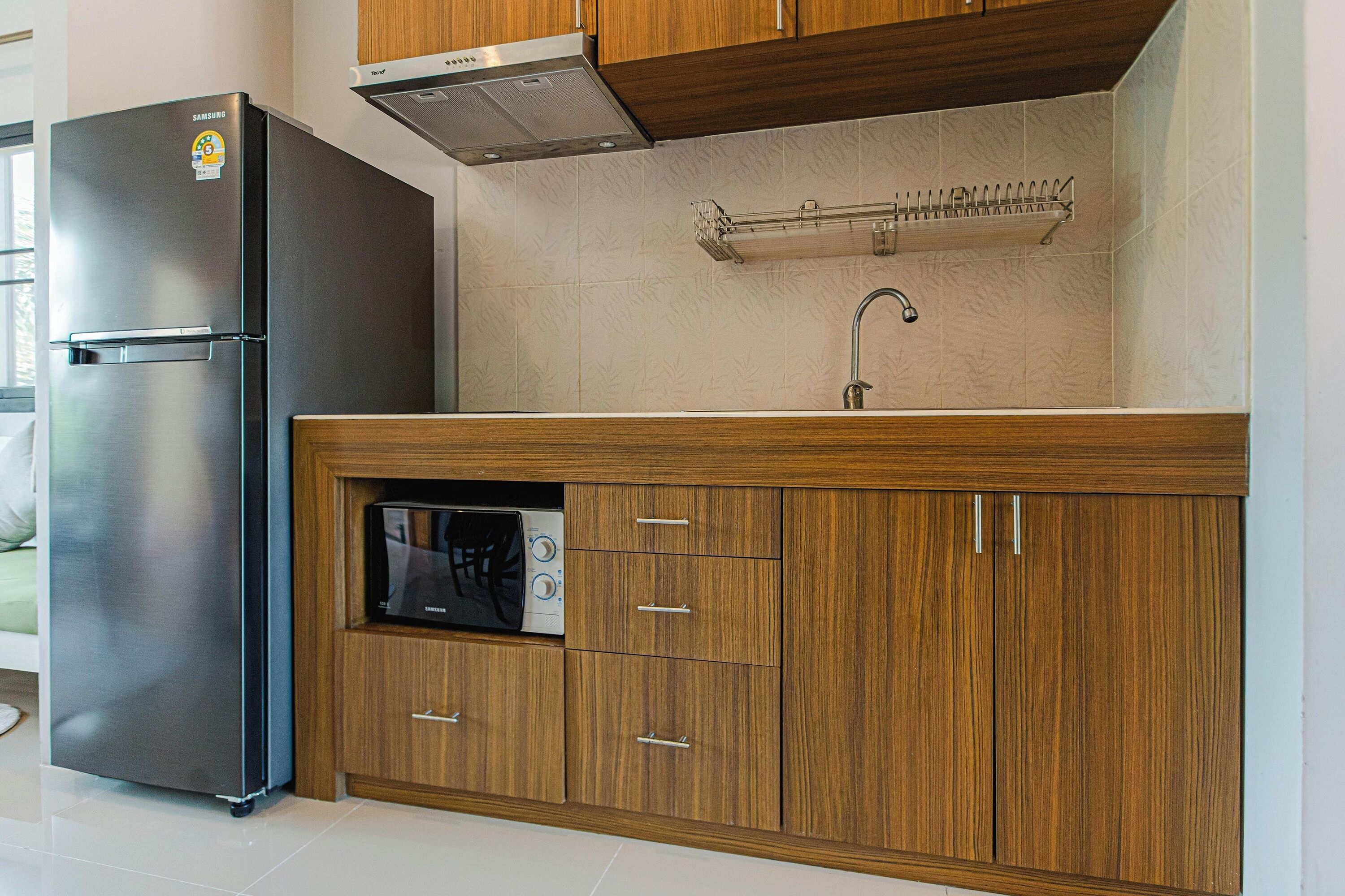 Una cocina con refrigerador de acero inoxidable, gabinetes de madera, lavavajillas empotrado y pileta de acero inoxidable.