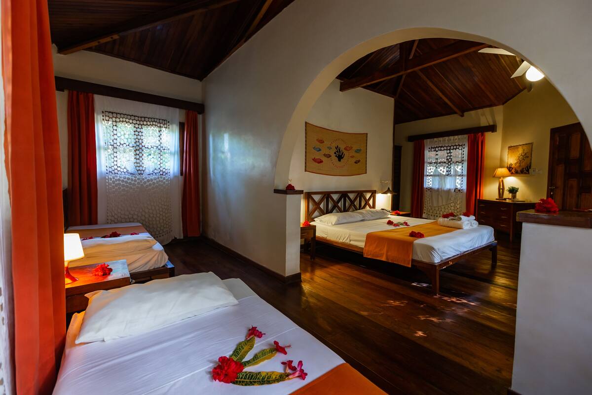 A hotel room with two beds, wooden flooring, and a decorative wall hanging.
