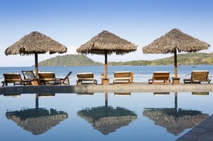 Una piscina al aire libre, sillones reclinables de piscina