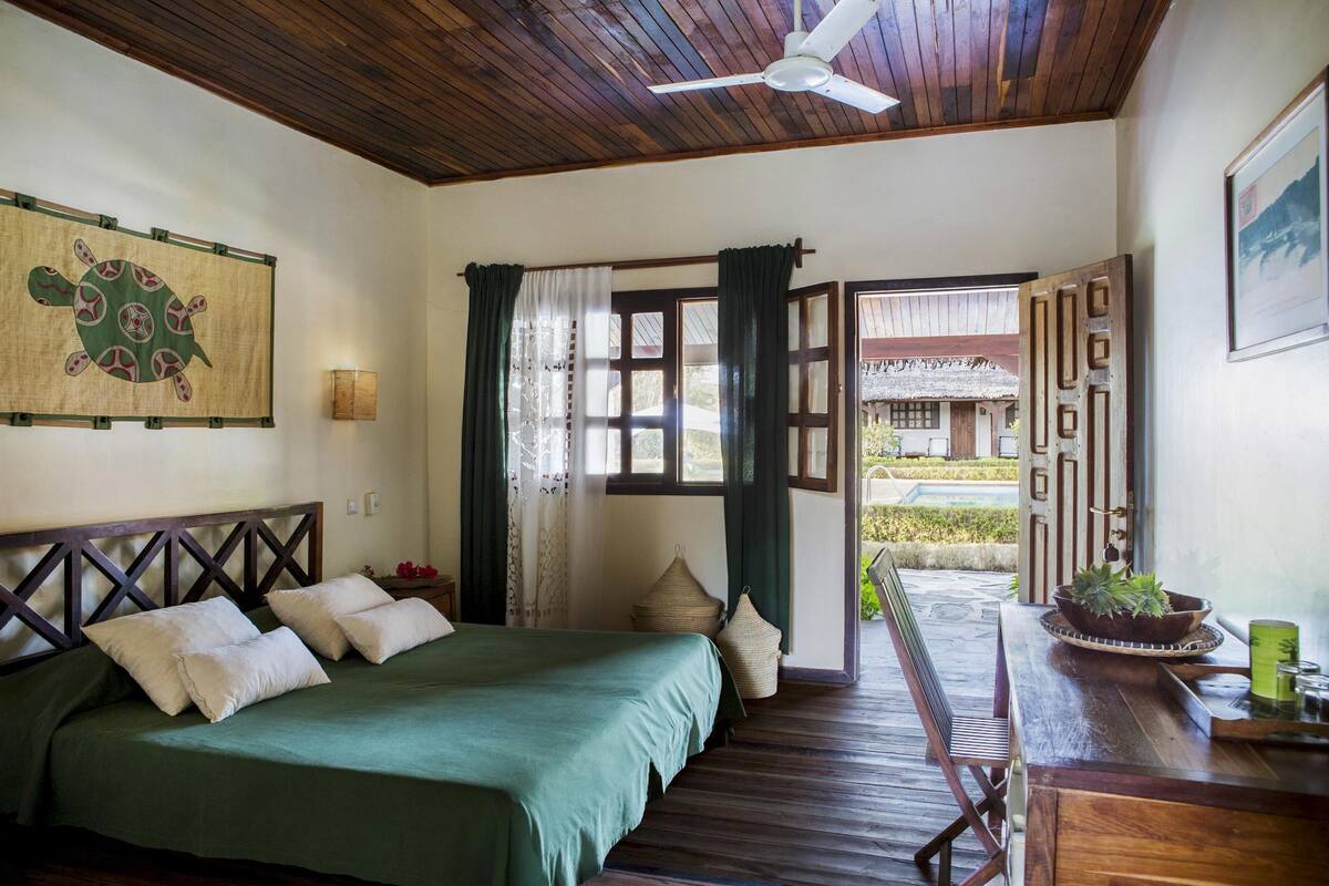 A room with a bed, wooden ceiling, and a view of the outside.