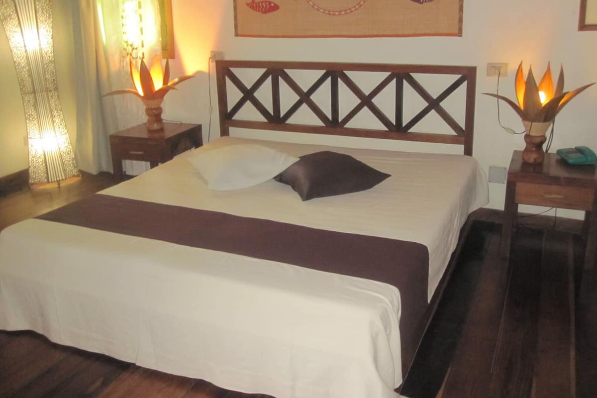 A neatly made bed with a wooden headboard, two bedside lamps, and a wall decoration.