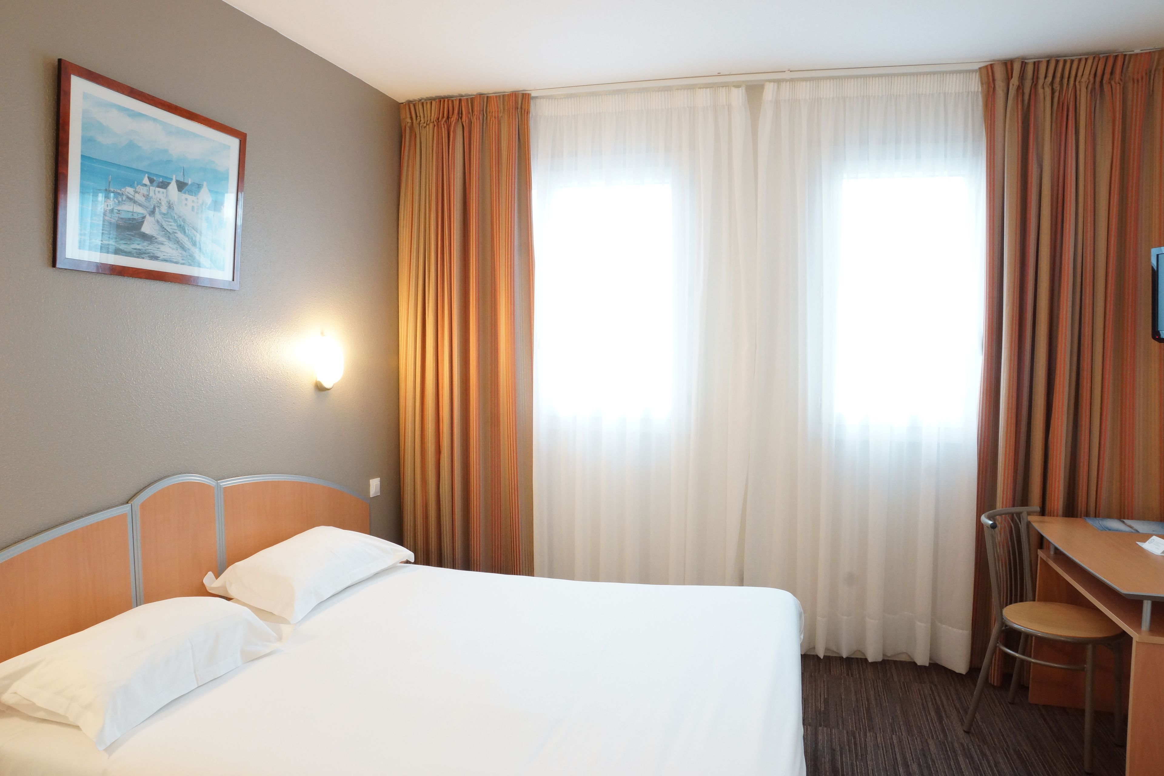 Een hotelkamer met een bed, een bureau en een stoel.