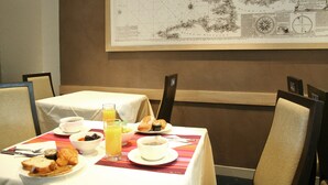 Mesa de jantar posta com itens de café da manhã, um mapa na parede e vista para o mar.