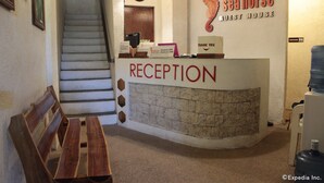 Un área de recepción con mostrador de piedra, banco de madera y una escalera.