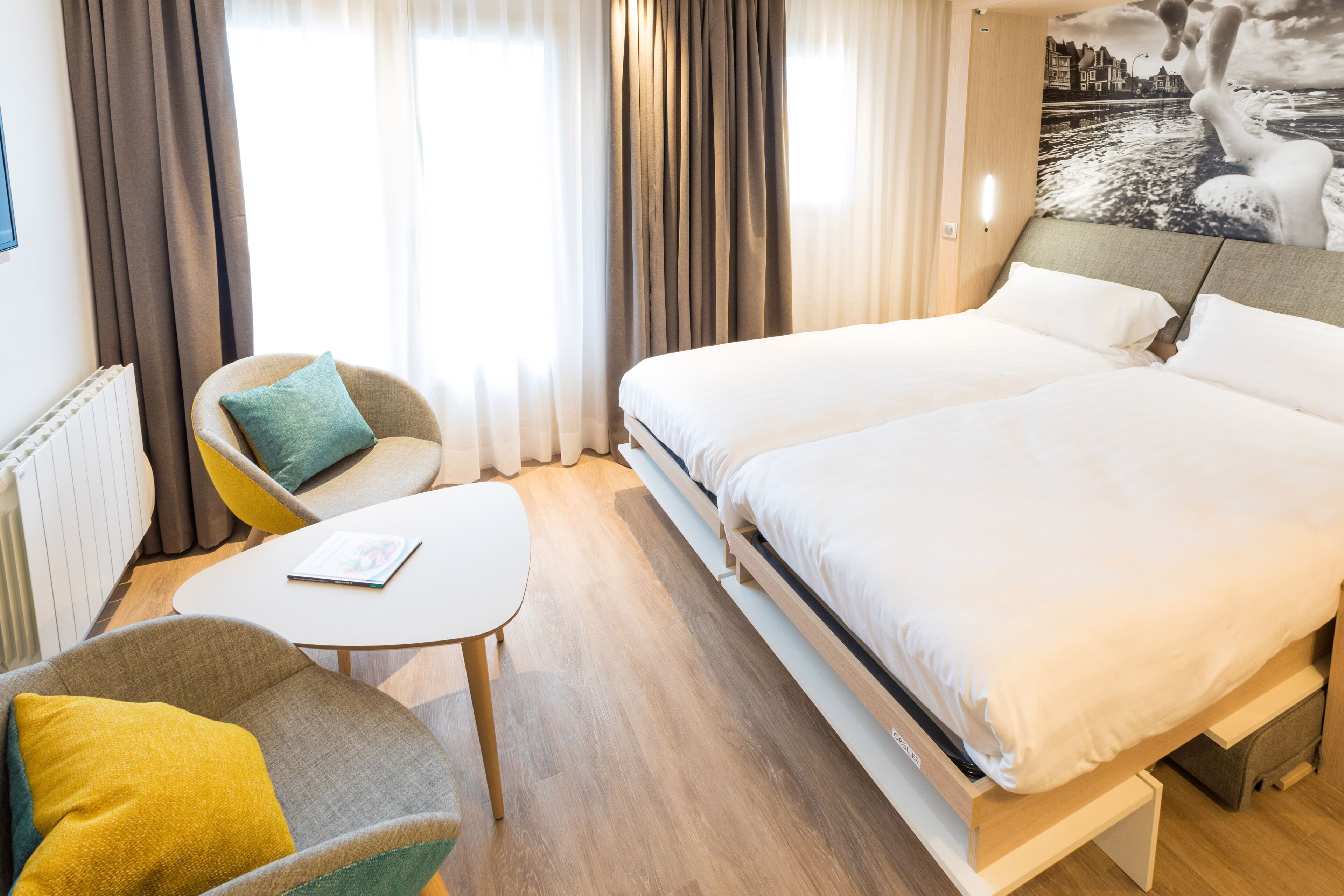 Une chambre d’hôtel avec un grand lit, une petite table, une chaise et une vue sur la mer par la fenêtre.
