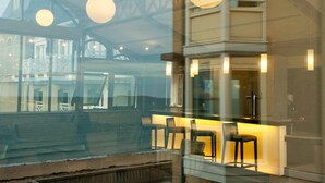 A modern interior with a glass partition, seating area, and pendant lighting. - Résidence Neptunia (Saint-Malo)