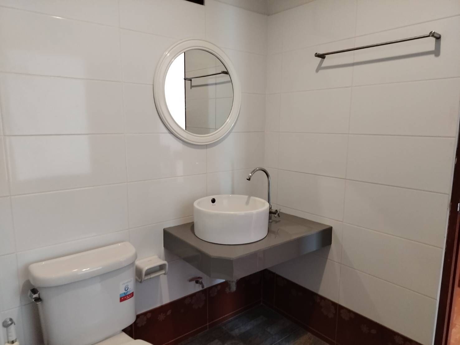 A bathroom with a toilet, sink, mirror, and towel rack.
