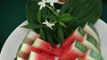 A plate of watermelon slices arranged in a pattern, with green leaves and white flowers on a white plate.