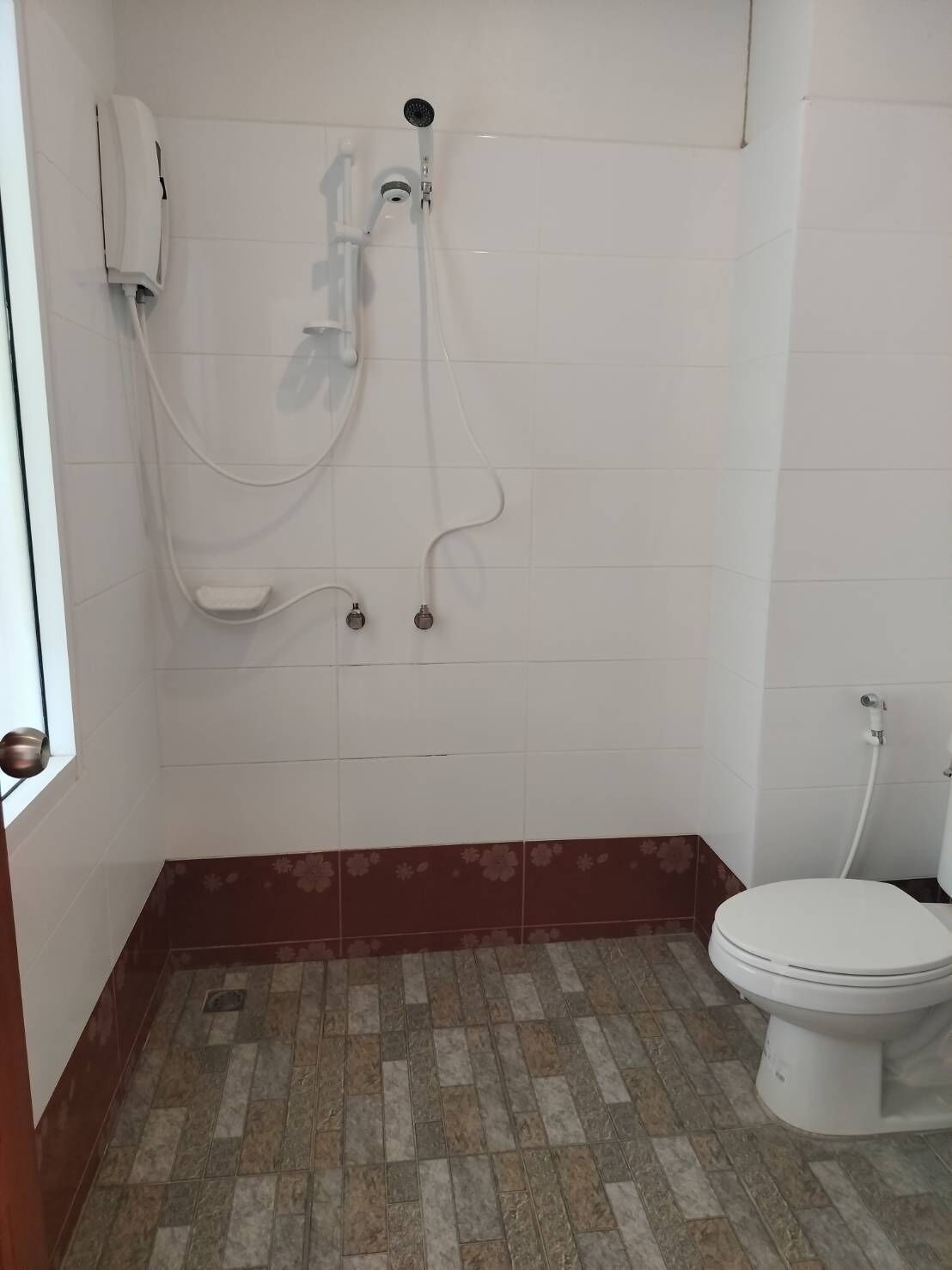 A bathroom with a shower, toilet, and a tiled floor.