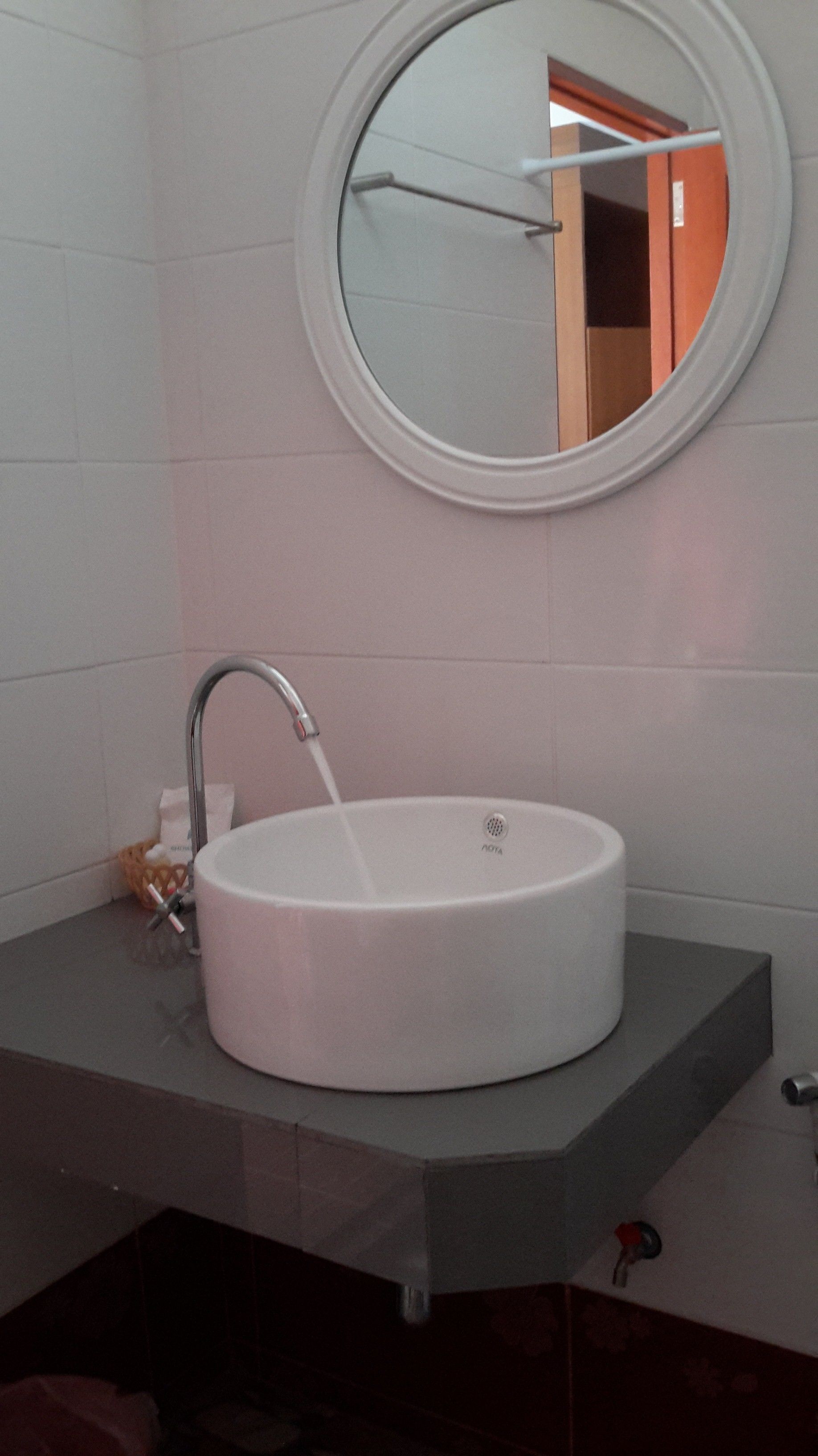 A bathroom with a round mirror, a white sink, and a towel rack.