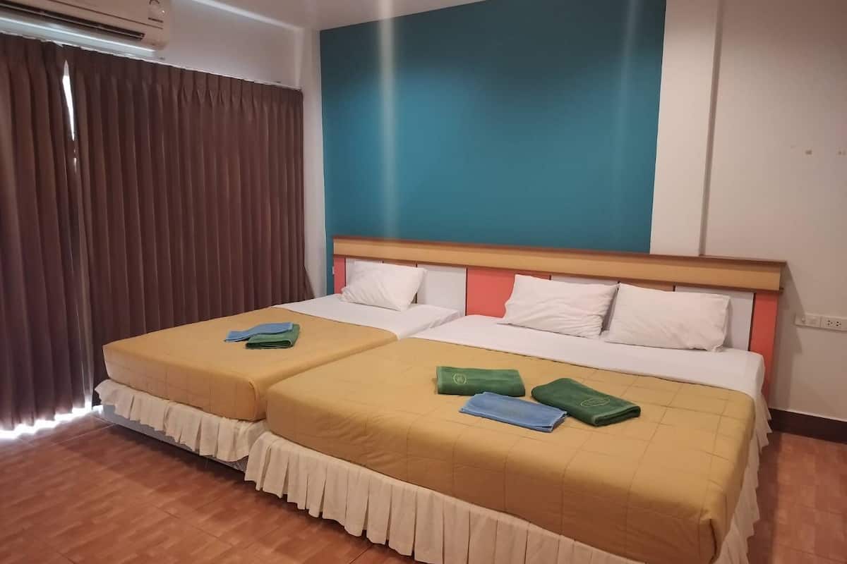 A hotel room with two beds, a large window with curtains, and a wall painted in blue and teal.