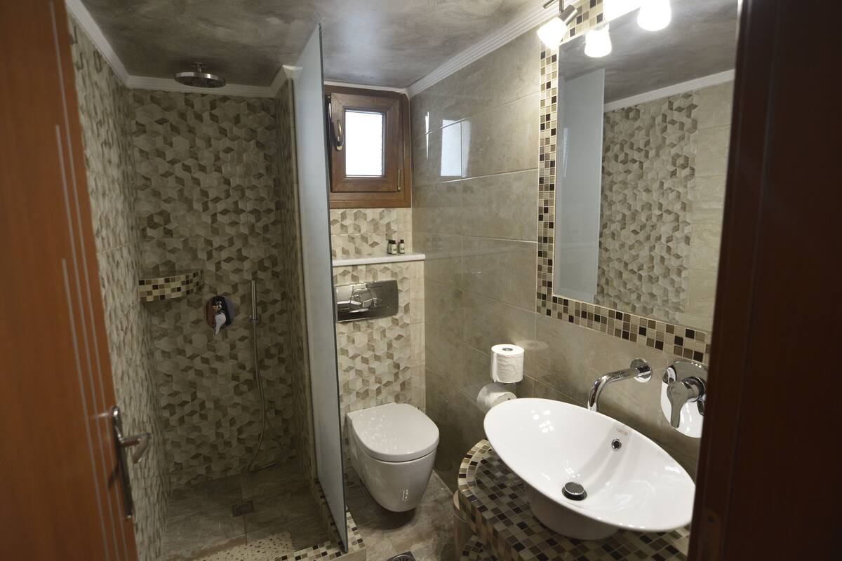 A bathroom with a shower, toilet, sink, and a mirror.