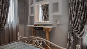 A bedroom with a bed, a vanity with a mirror, and a television mounted above the mirror. - Polydefkis Apartments (Santorini)