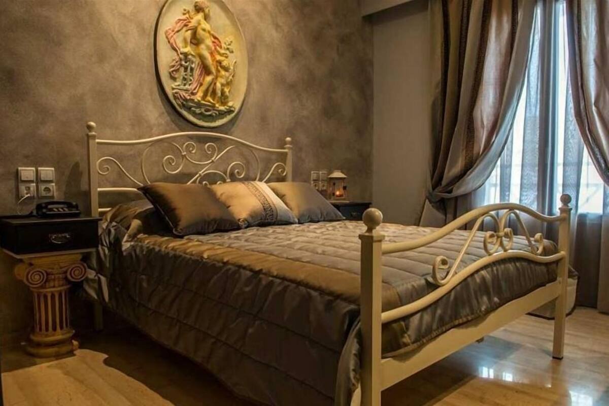 A bedroom with a bed, a nightstand, a lamp, and a decorative wall piece.