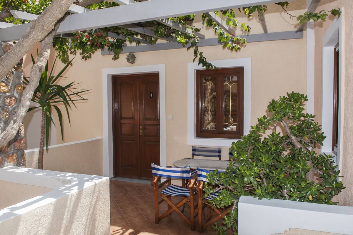 An outdoor patio with a table and chairs, a wooden door, and a window with decorative glass.