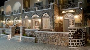 A stone facade with balconies and a sign for "Polydelfis Apartments". - Polydefkis Apartments (Santorini)