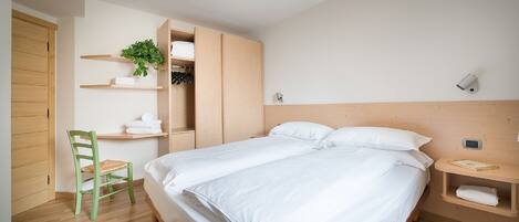 Une chambre avec un lit, une chaise, une étagère avec des serviettes et une plante.