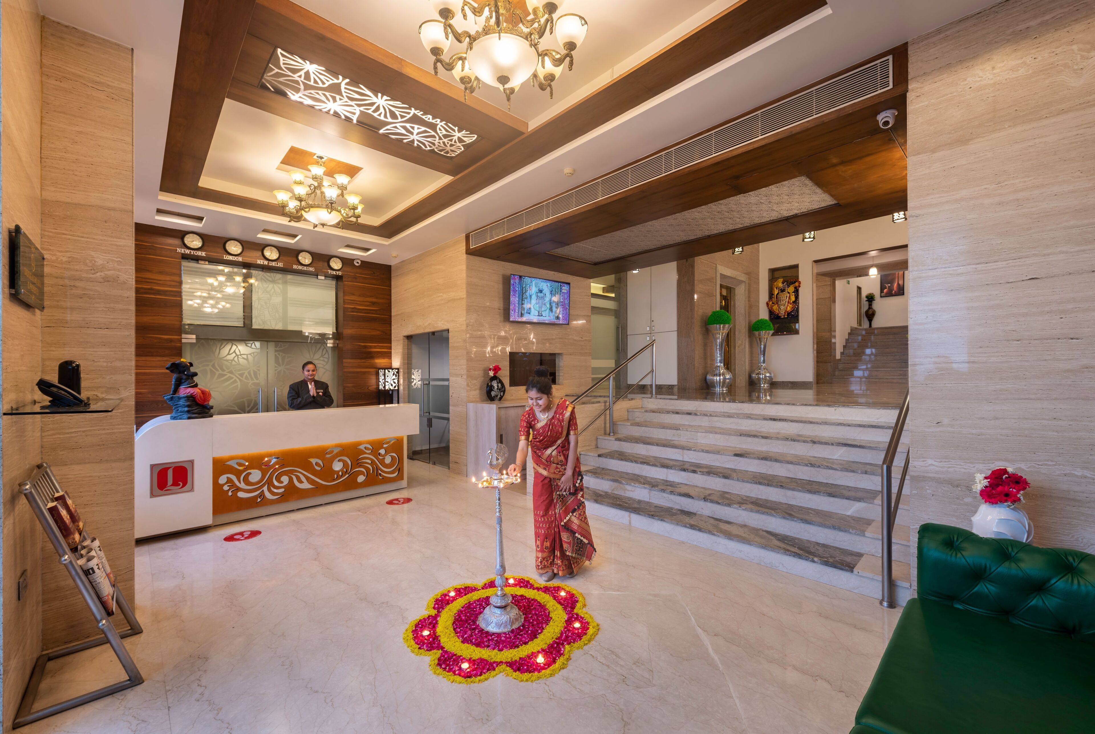 A hotel lobby with a reception desk, a staircase, and a decorative floor pattern.