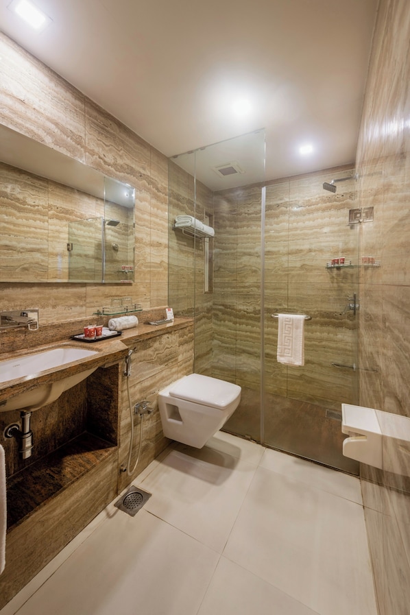 Un baño moderno con tocador de mármol, cabina de ducha de vidrio y un área separada para el inodoro.