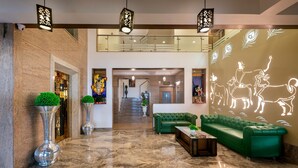 Eine großzügige Lobby mit einem grünen Sofa, einem Couchtisch und dekorativen Vasen.