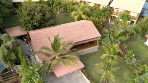 A multi-story hotel with a red-roofed building, a covered parking area, and lush greenery.