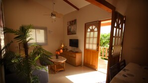 A cozy living room with a television, a small table, and a plant.