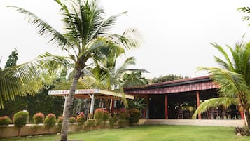 A building with a covered outdoor area, a sign indicating parking, and a well-maintained lawn.