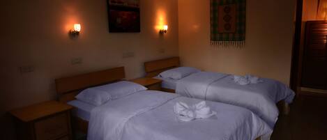 Habitación de hotel con dos camas, cabeceros de madera, mesitas de noche e iluminación en la pared.