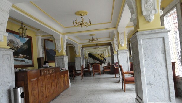 A reception area with a marble floor, wooden reception desk, and a chandelier.