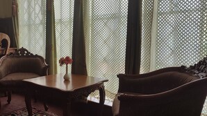 A traditional room with a wooden table, two upholstered chairs, and a vase with flowers.