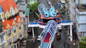 A street with a unique pedestrian bridge featuring a butterfly design.
